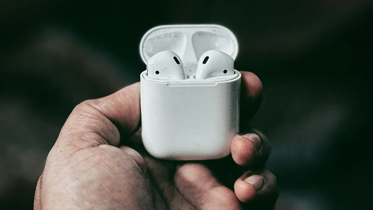A person holding AirPods in their hand