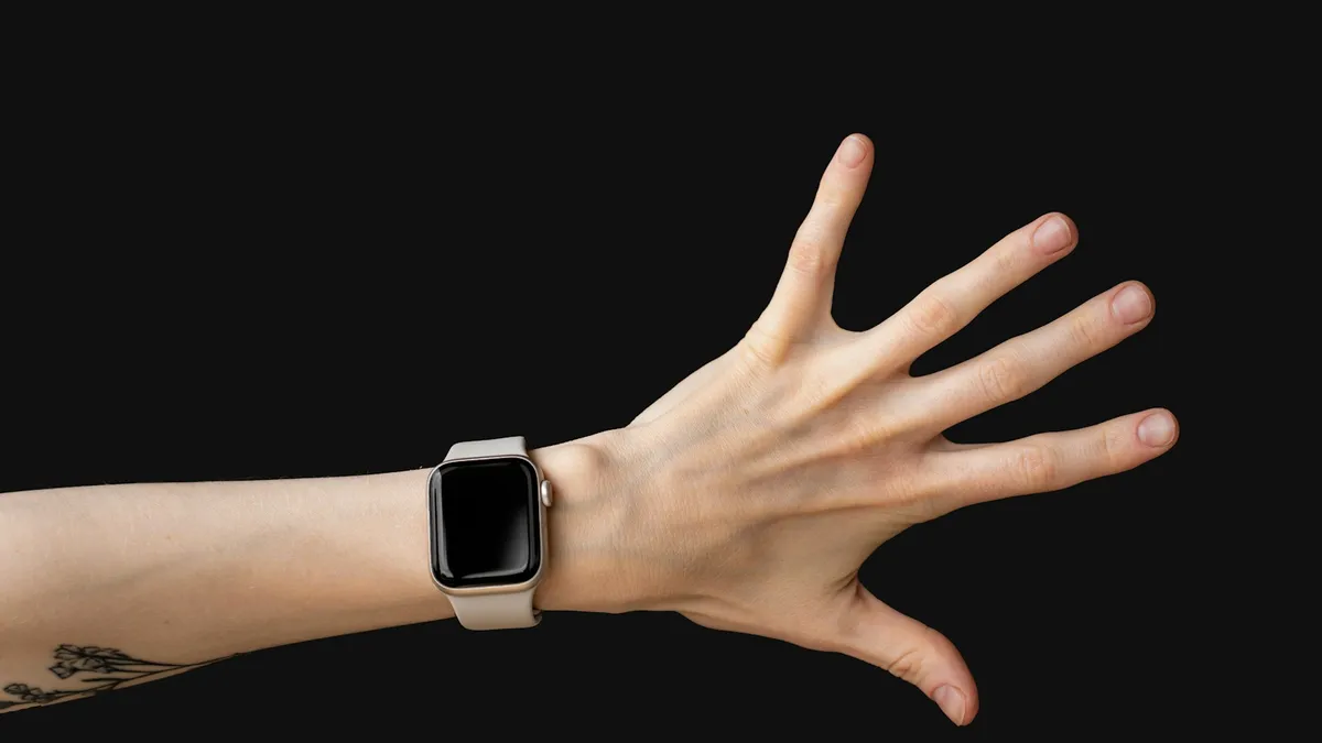 A hand with an Apple Watch on the wrist against a black background