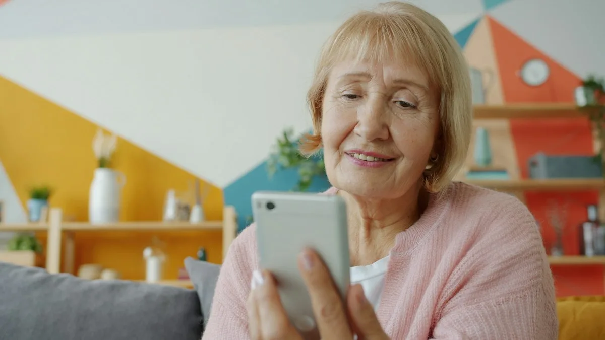 An elderly woman smiling while looking at a smartphone