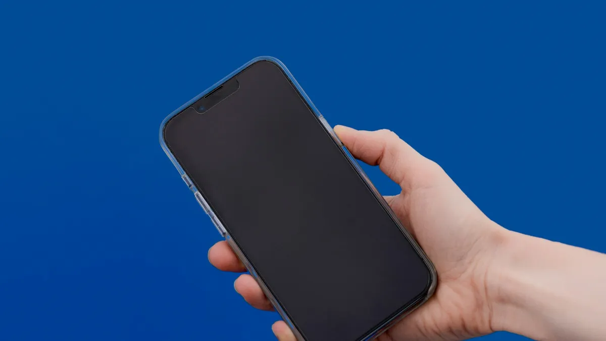 A hand holding a smartphone against a blue background