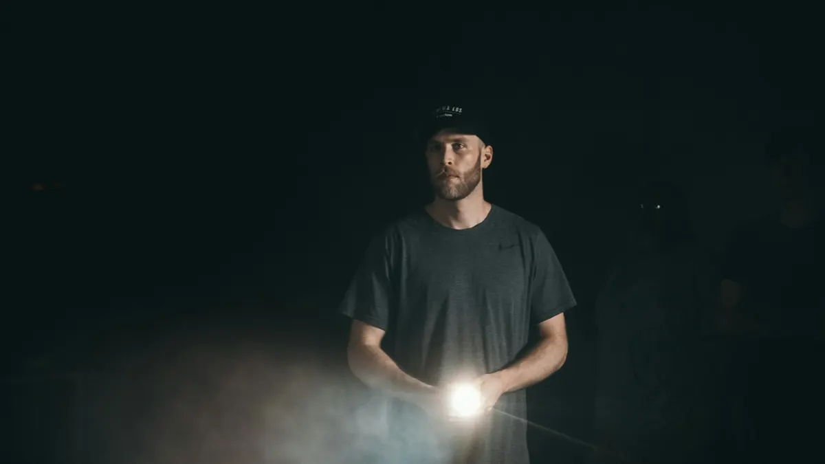 Man holding a turned on flashlight in the dark