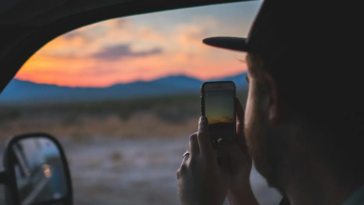 A man holding a smartphone while sitting inside a car