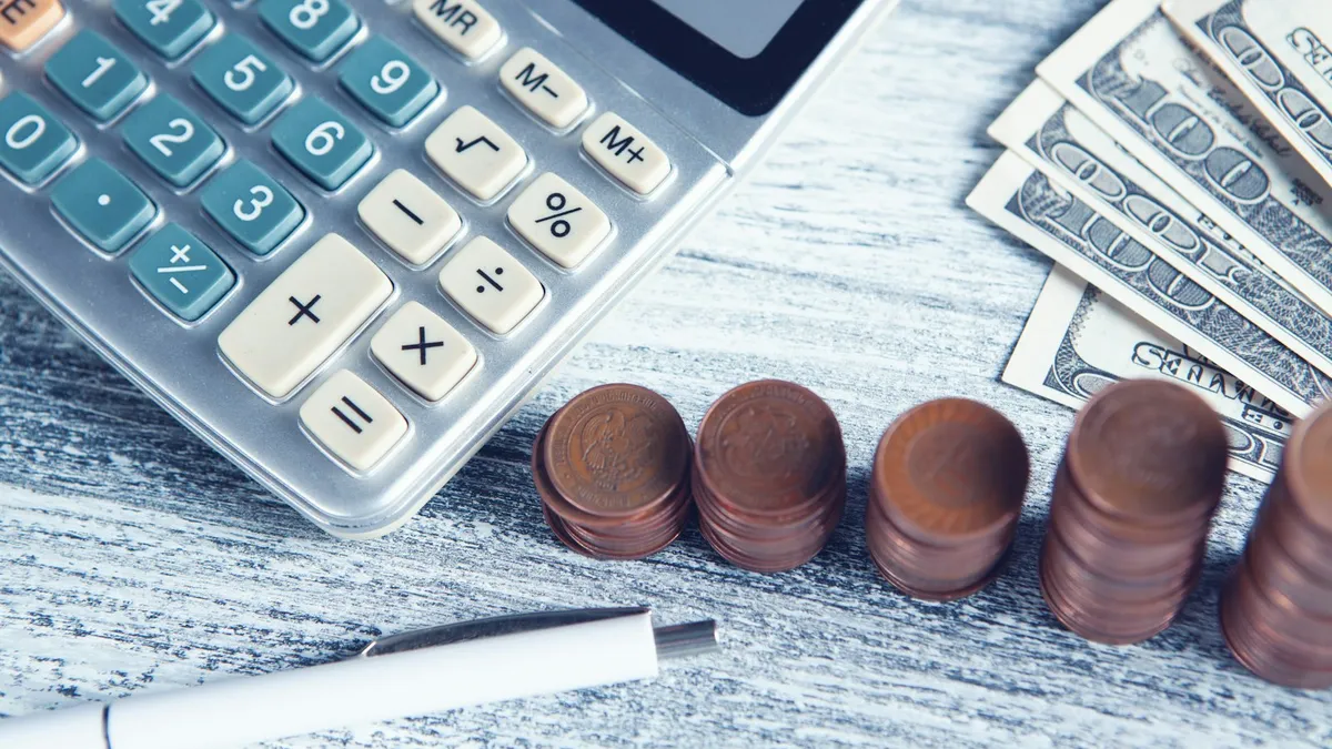 A calculator, pen and money on a table