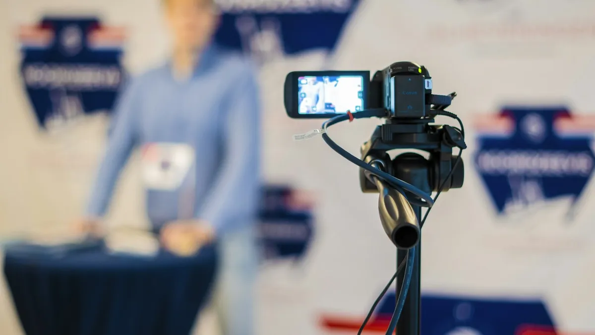 A person standing behind a microphone with a cell phone on a tripod