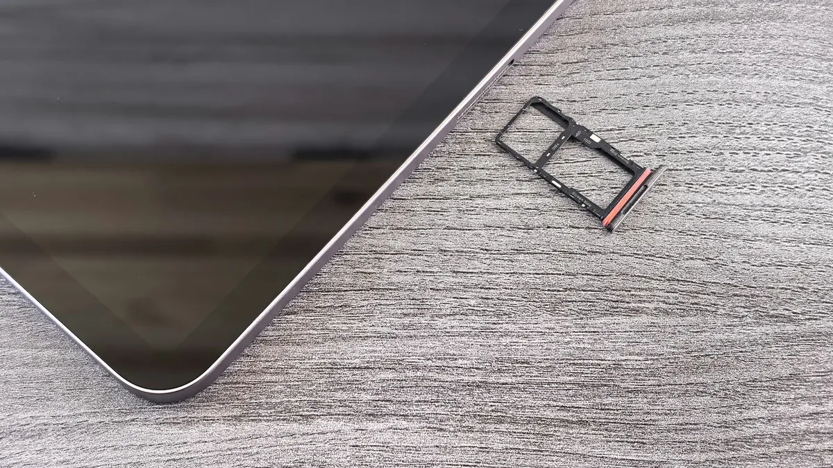 A device with its SIM card tray pulled out on a gray desk